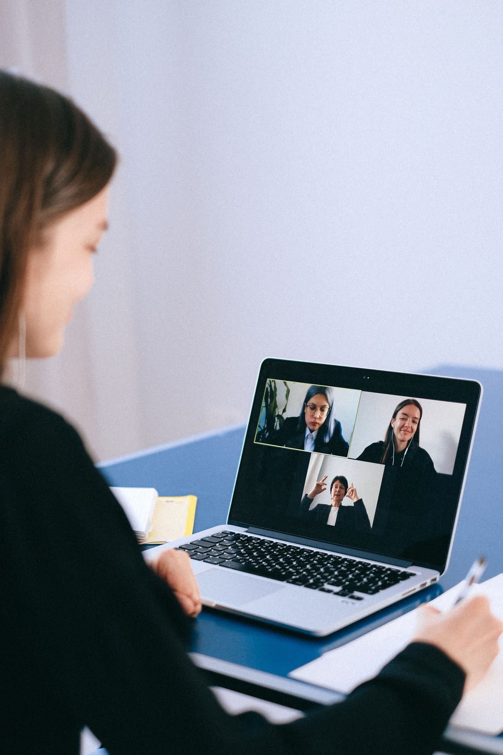 Pessoa em uma reunião por vídeo com três participantes na tela do notebook