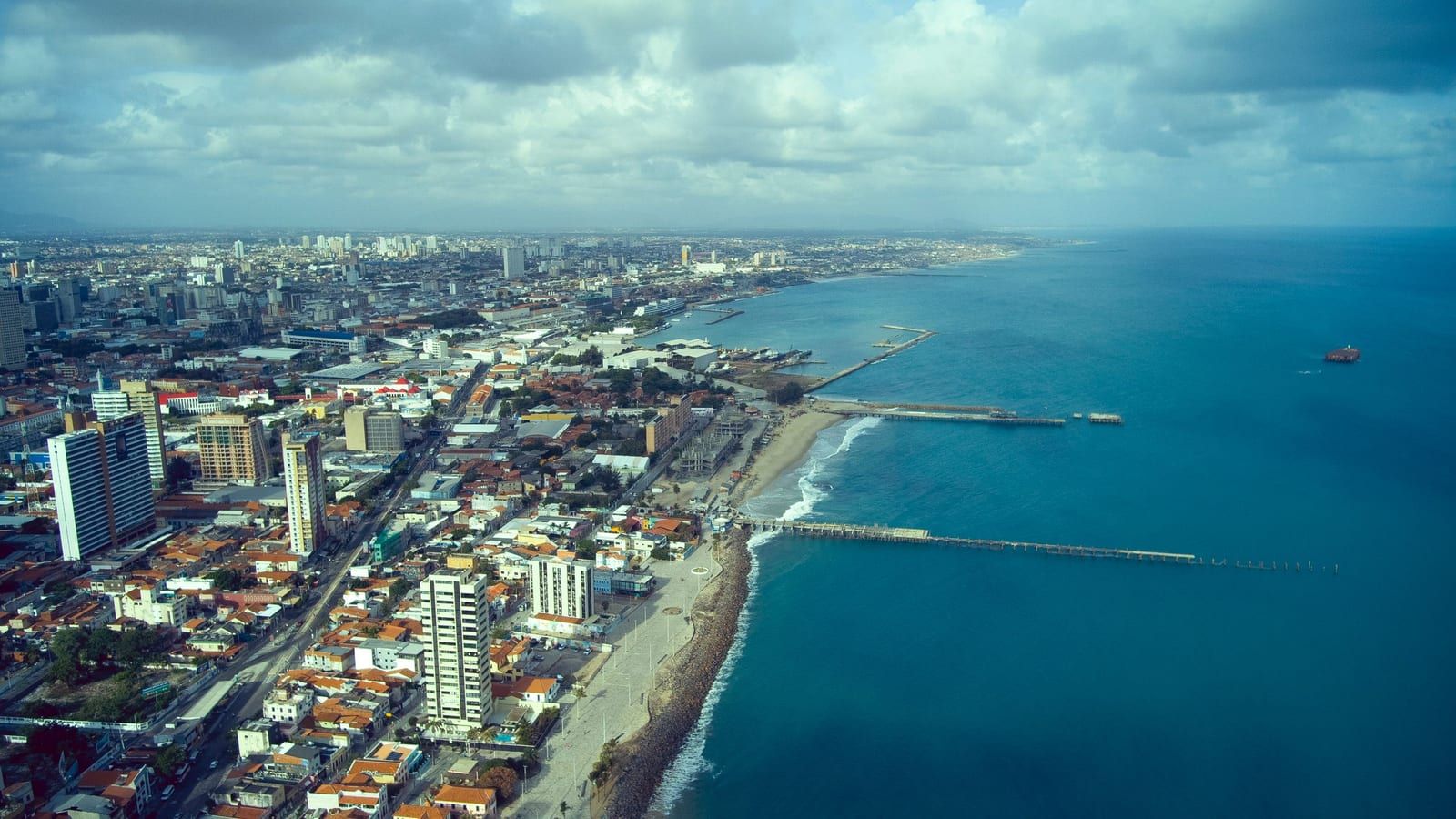 Vista aérea de Fortaleza, com prédios à beira-mar e o oceano