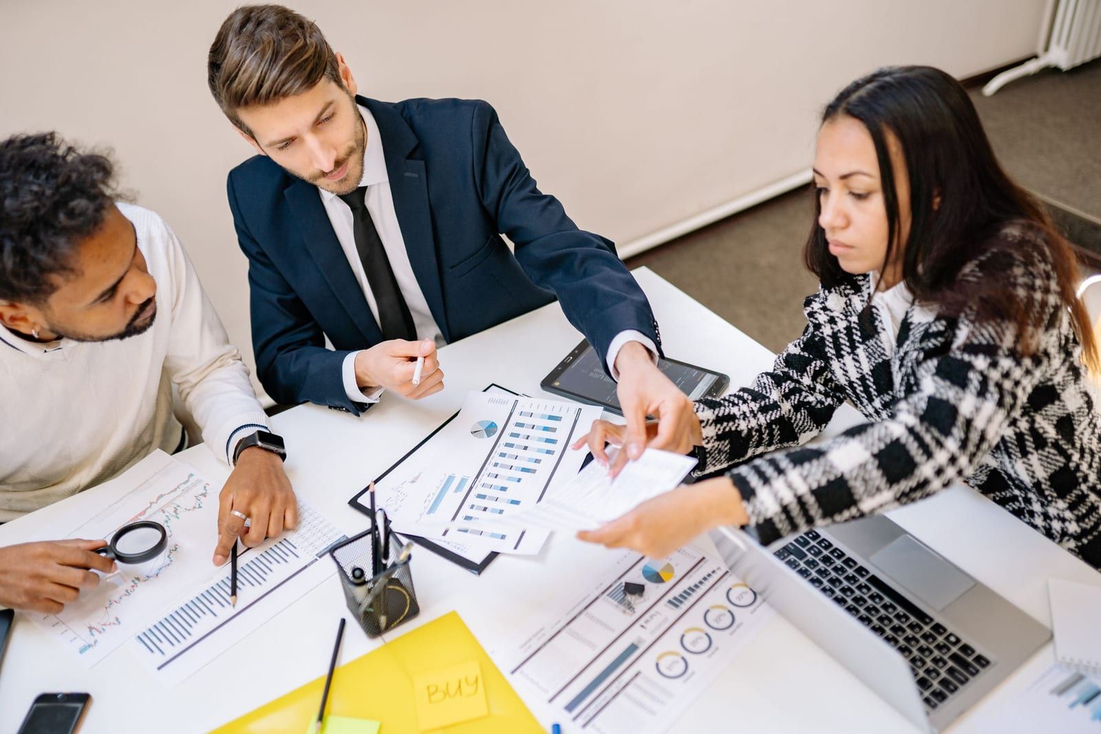 Equipe reunida em volta de uma mesa analisando gráficos impressos